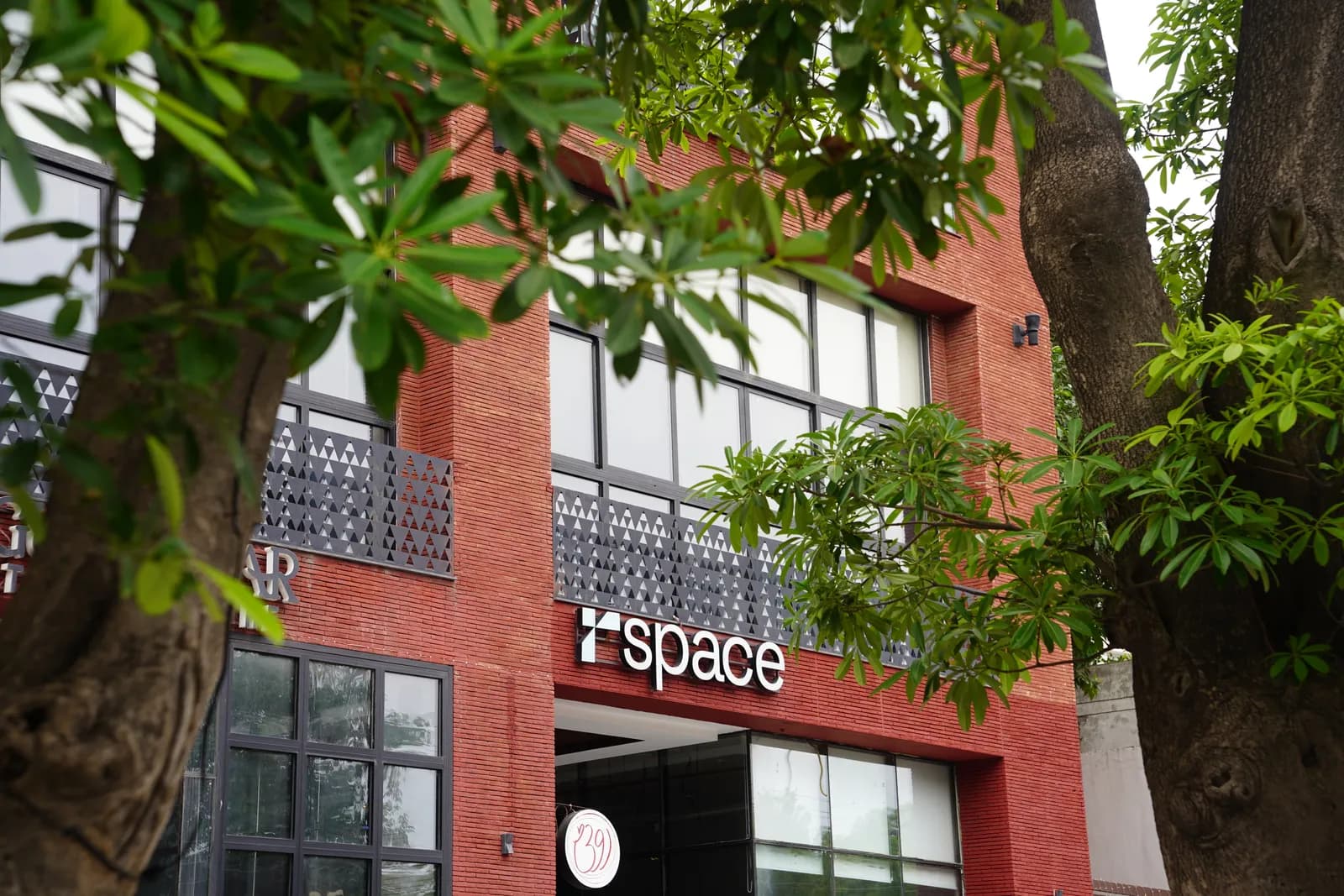The red-brick exterior of RSpace Gulmohar Trade Centre with the r.space sign, framed by trees