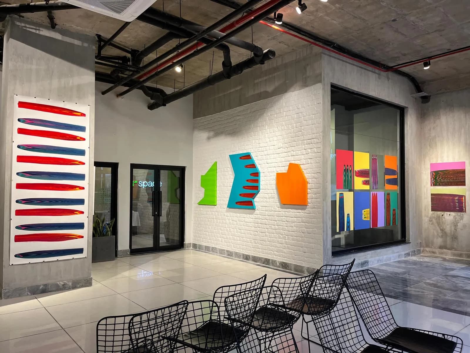 A lounge at RSpace Gulmohar Trade Centre with colourful contemporary art and wire chairs